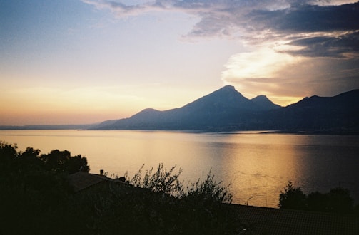 A tranquil lakeside resort with mountain backdrop at sunset.