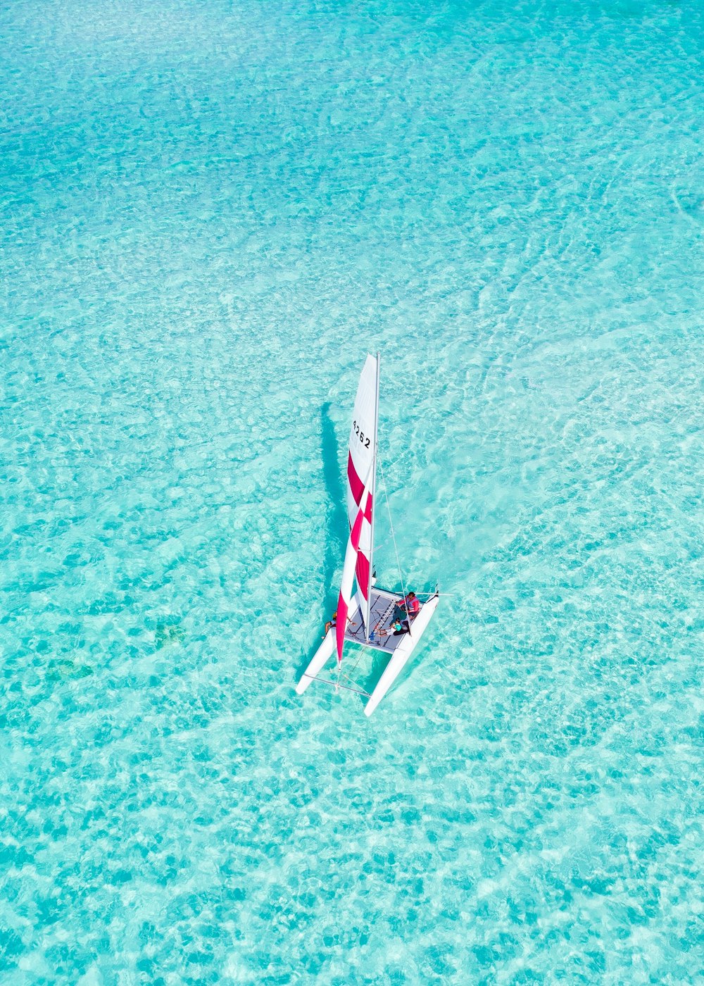 a red and white sail boat in the ocean