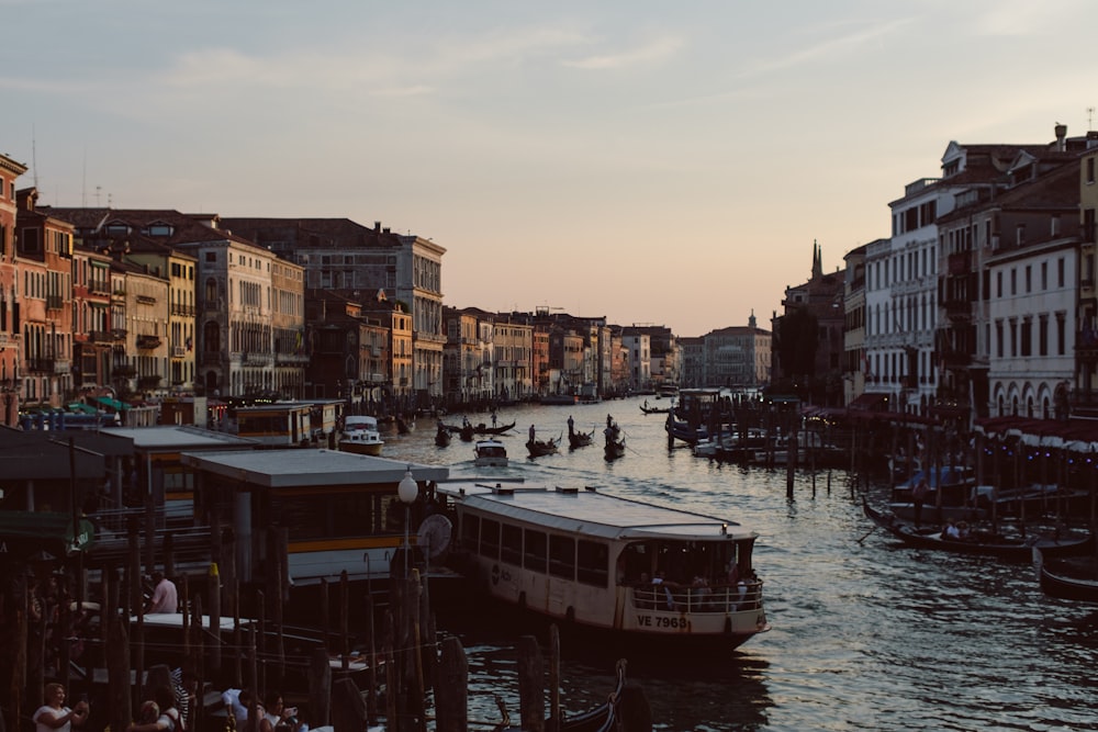 a river filled with lots of boats next to tall buildings