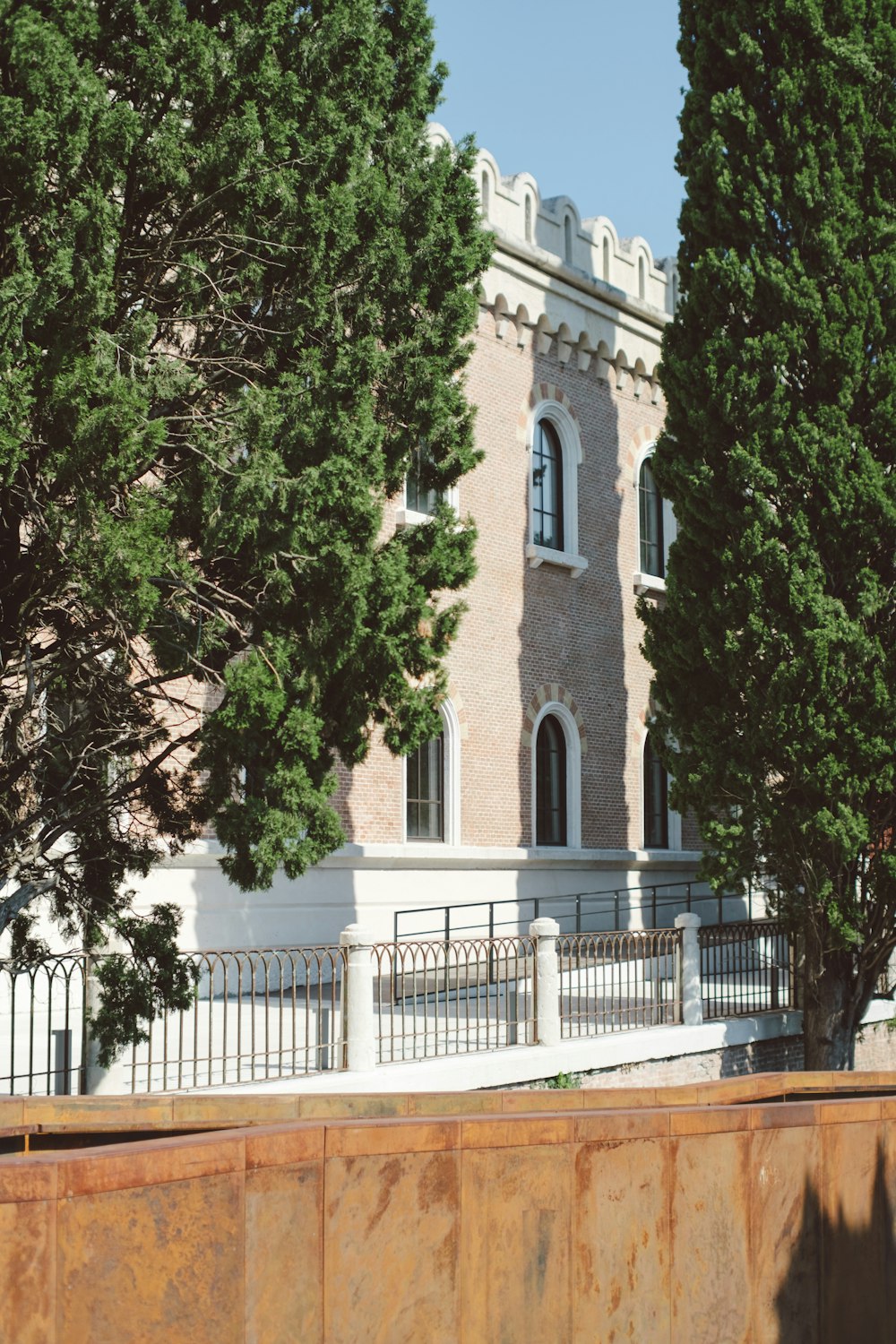 a tall brick building with a white fence around it