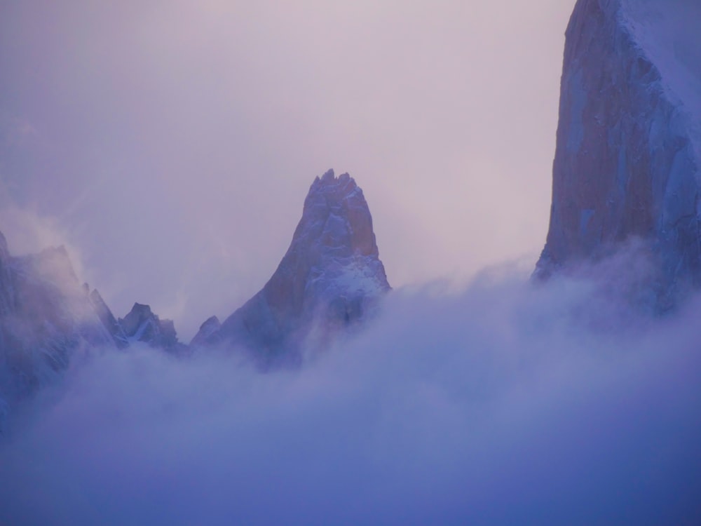 a mountain covered in snow and clouds with a sky background