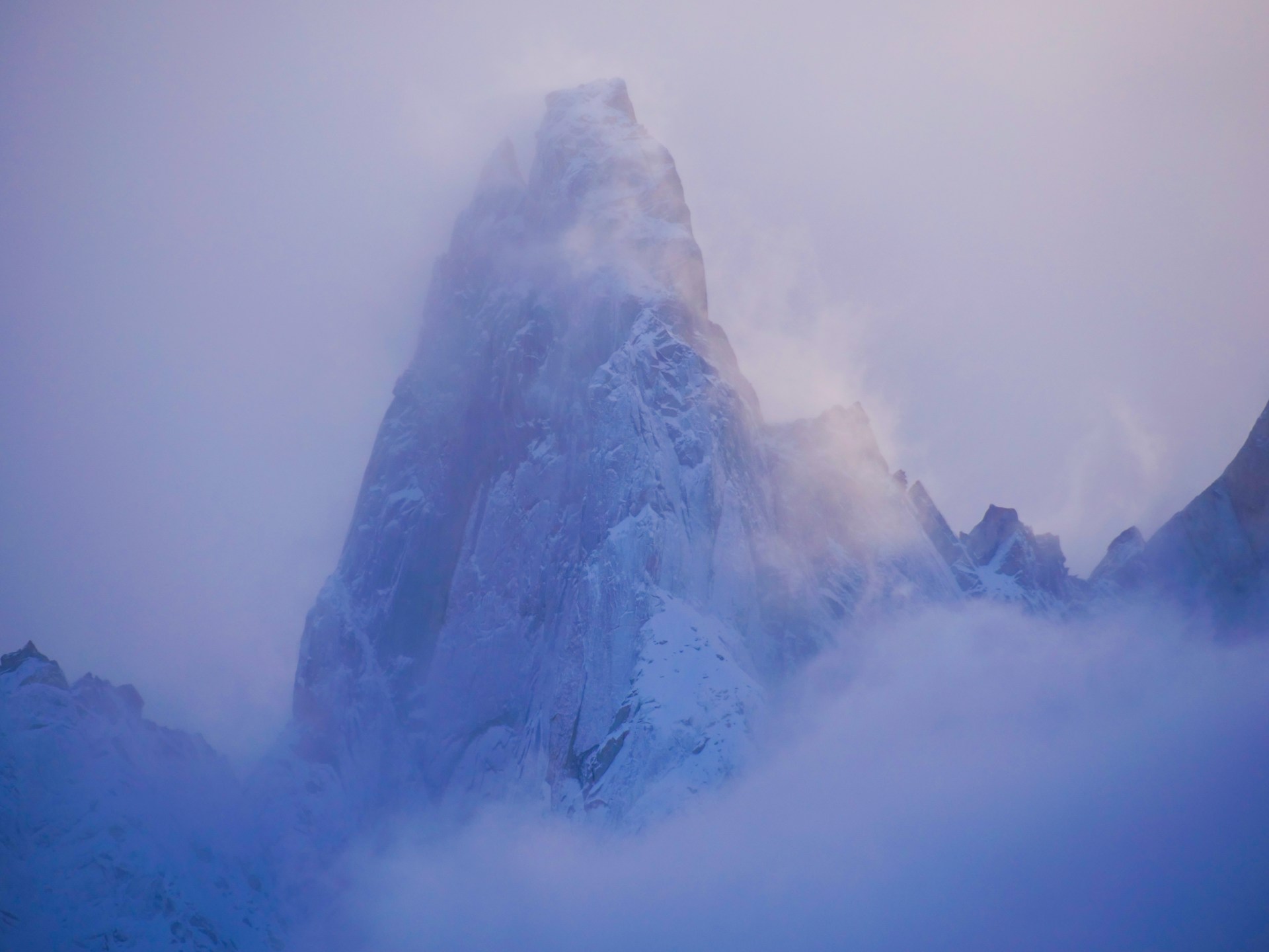 a very tall mountain covered in snow and clouds