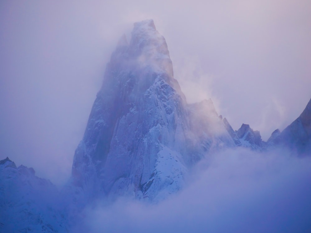 a very tall mountain covered in snow and clouds