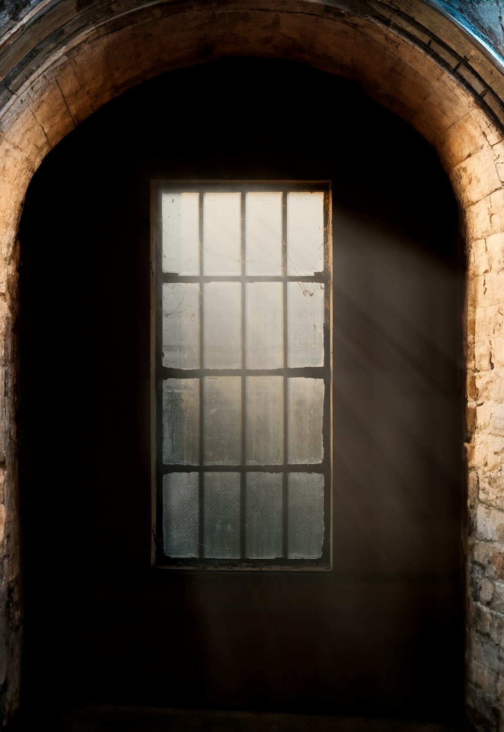 a window in a brick wall with a light coming through it