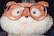 A plush toy resembling an animal with a fluffy texture, wearing oversized eyeglasses. The toy features a mix of brown and cream colors, and has a playful, surprised expression with big eyes.
