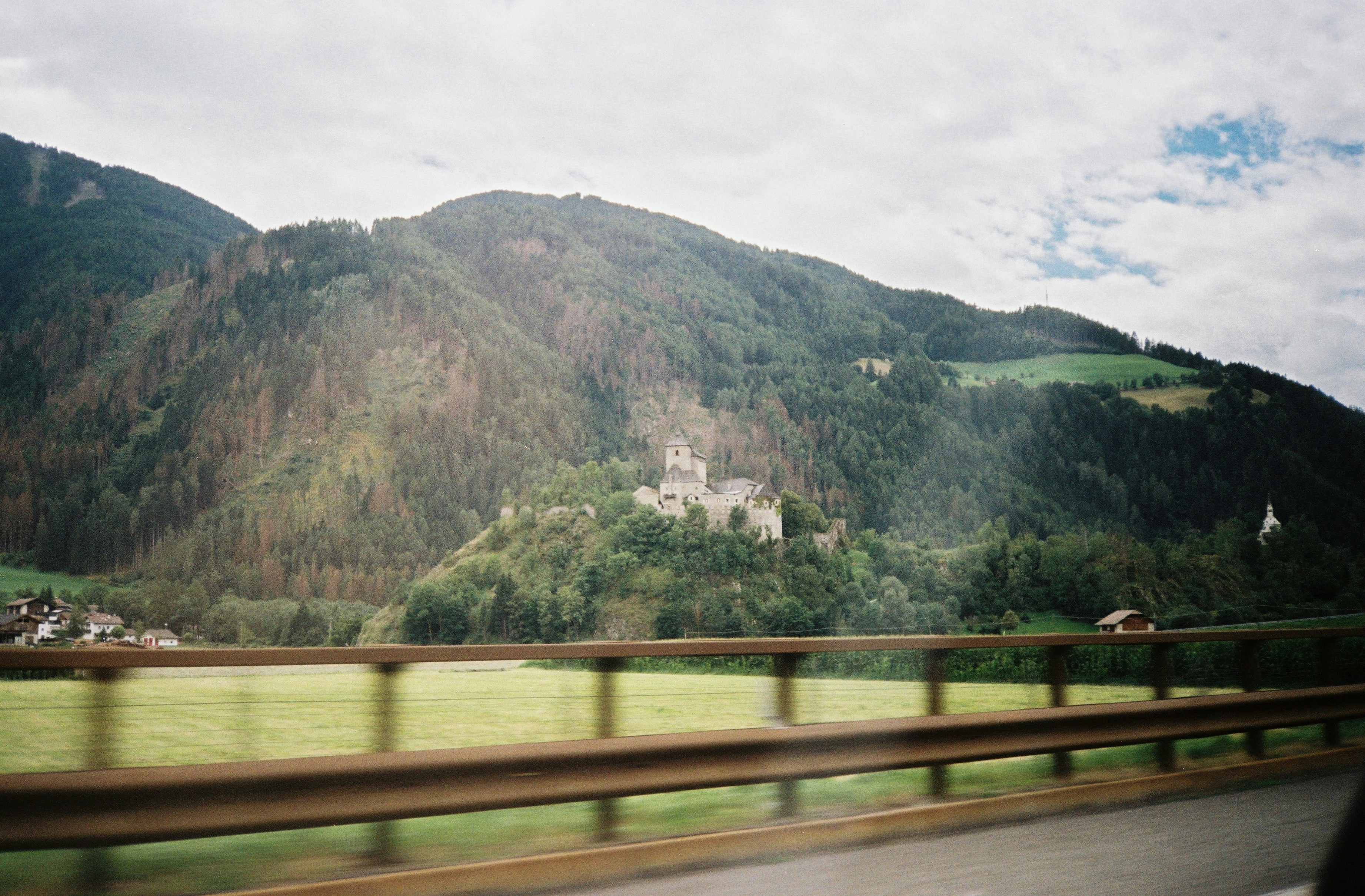 a view of a castle in the mountains from a moving car
