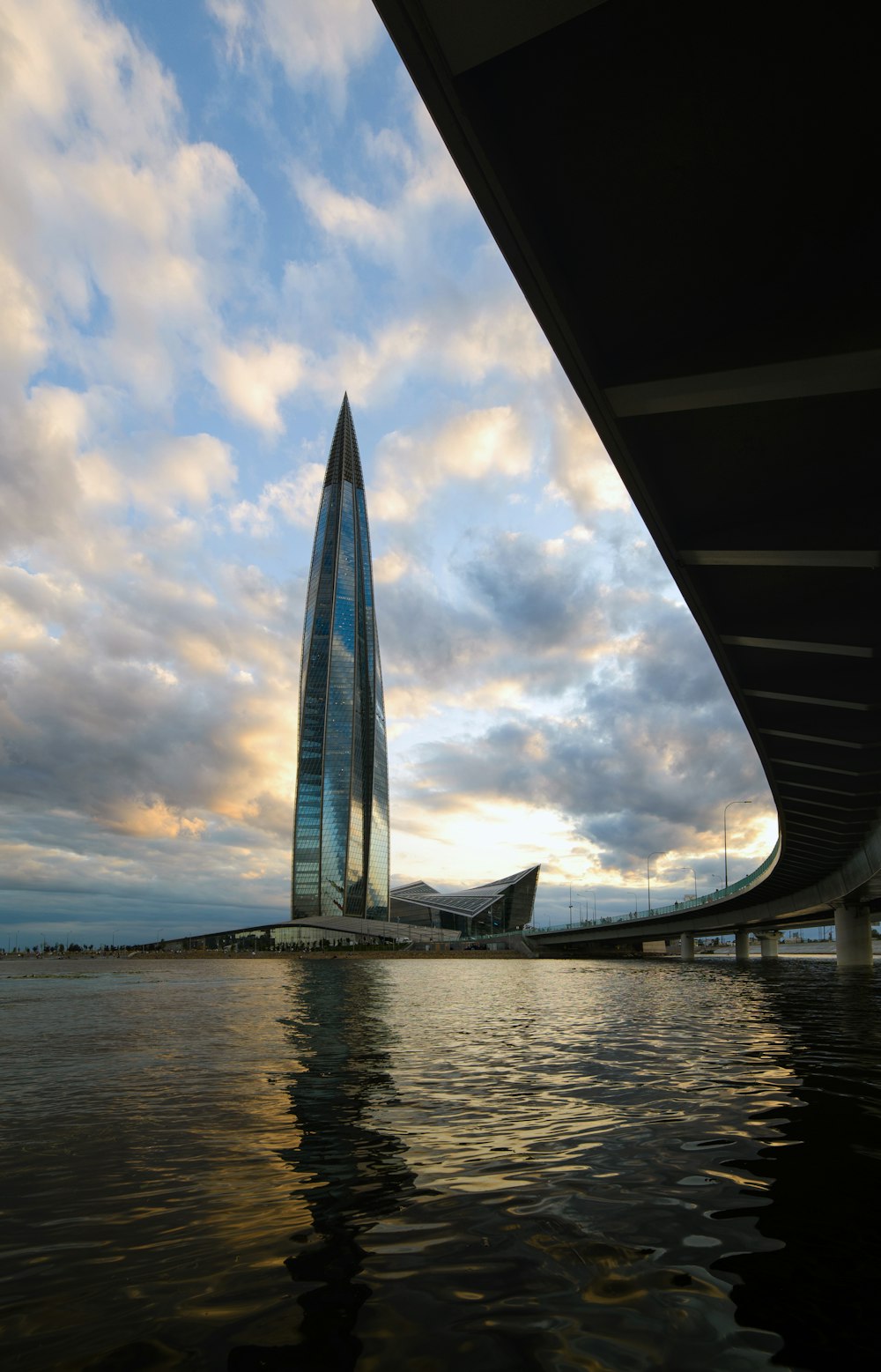 a tall building sitting next to a river under a cloudy sky