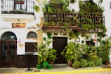 A charming boutique hotel facade nestled among flowering plants and rustic architecture.