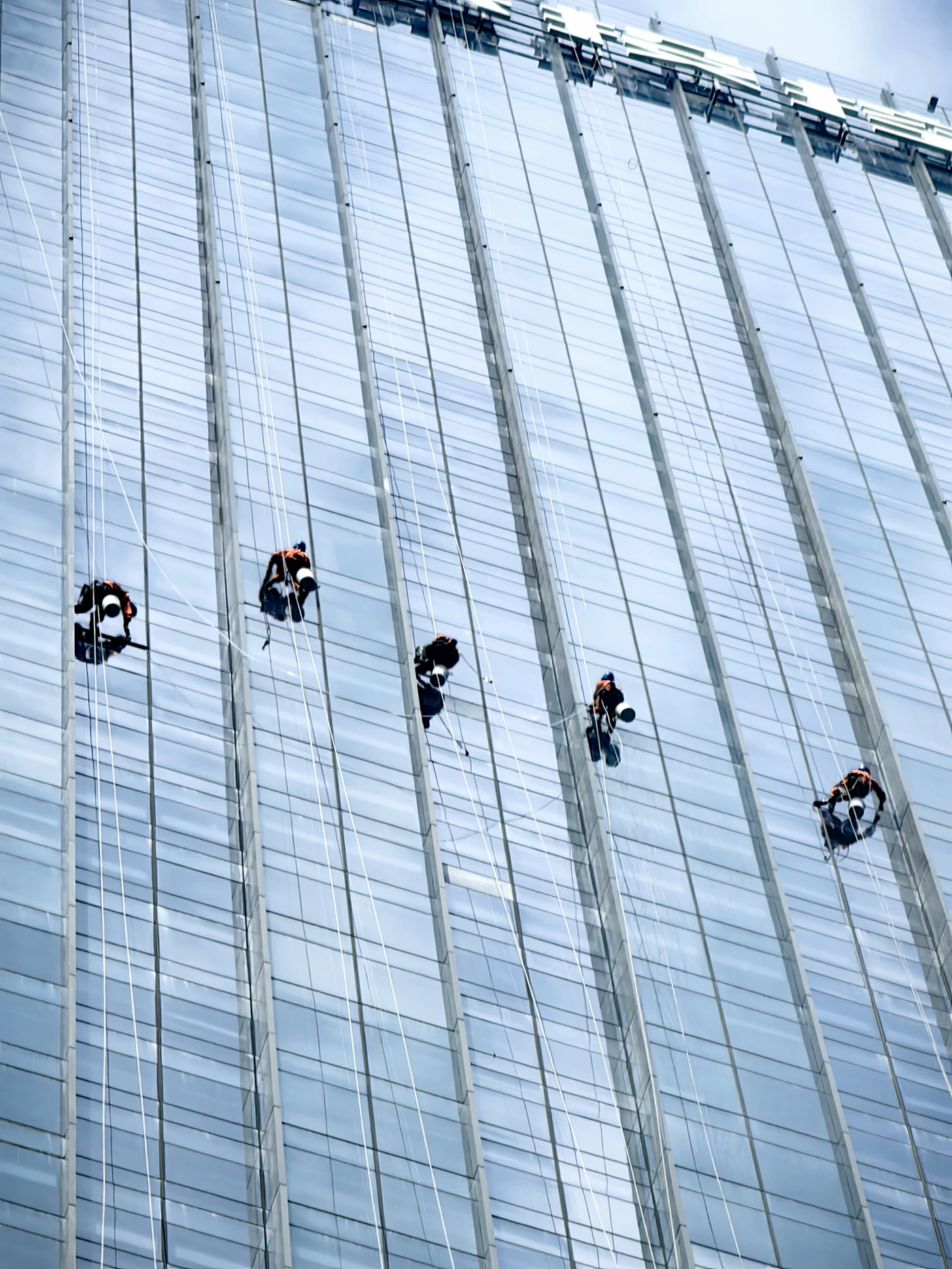 Técnicos de trabajos verticales actuando en una fachada de edificio moderno en Valladolid