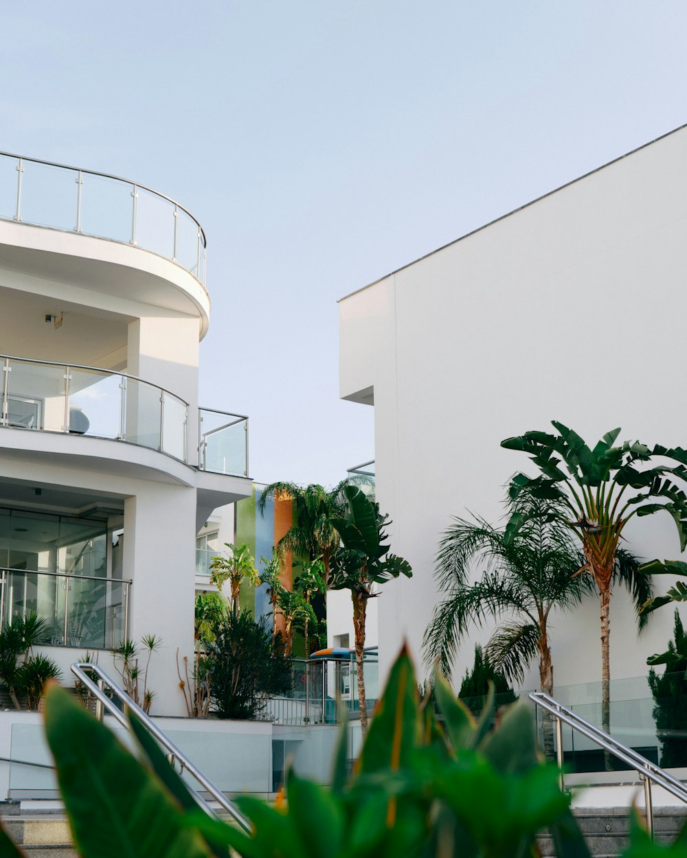 a white building with a balcony and palm trees in front of it