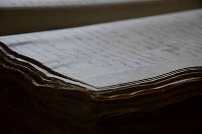 An old, thick stack of handwritten documents with visible texture and slight yellowing of the pages. The focus is on the edges, highlighting the layered, slightly curled paper.
