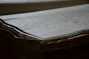 Stack of aged legal documents bound with a black ribbon, resting on a textured paper surface.