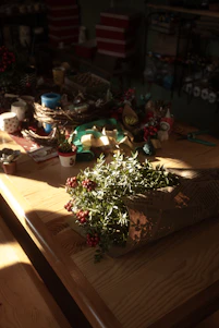 A warm, inviting workspace featuring wooden cutting boards, colorful soaps, and paper crafts in progress on a rustic table.