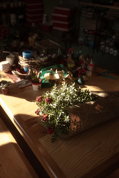A warm afternoon light bathes a rustic wooden table scattered with natural art materials and handmade crafts.