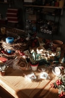 An assortment of colorful Christmas decorations including baubles, ribbons, and stars arranged on a rustic wooden table.