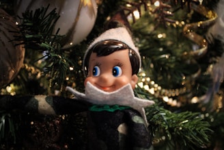 A festive holiday setup featuring Elf on the Shelf perched on a bookshelf with twinkling lights.