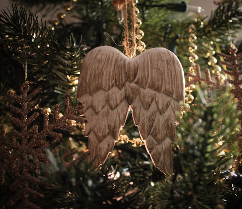 a wooden angel ornament hanging from a christmas tree
