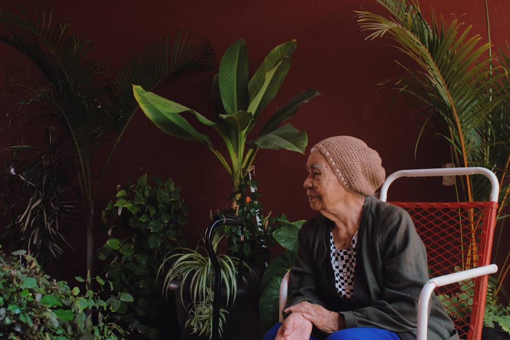 a woman sitting in a chair next to a potted plant