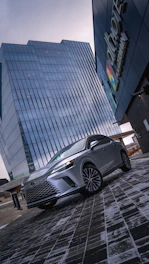 A sleek Toyota LC300 parked against a modern city backdrop at sunset.