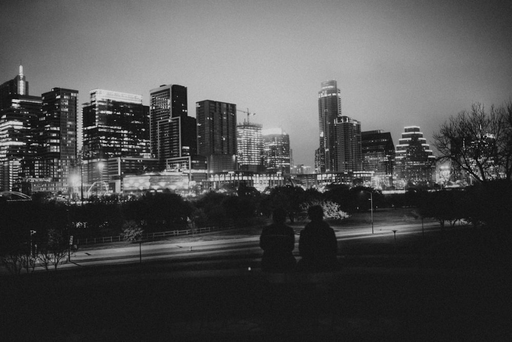 two people sitting on a bench in front of a city skyline