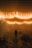 A dimly lit outdoor space with string lights hanging overhead in a warm glow. A solitary figure stands in the center of the scene, surrounded by wooden benches and fog that creates a mysterious ambiance.