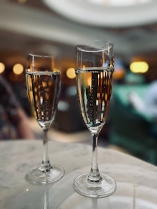 Close-up of crystal glasses filled with sparkling champagne resting on a minimalist marble countertop.