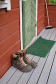 Hiking boots resting on a rustic wooden porch overlooking a forest trail.