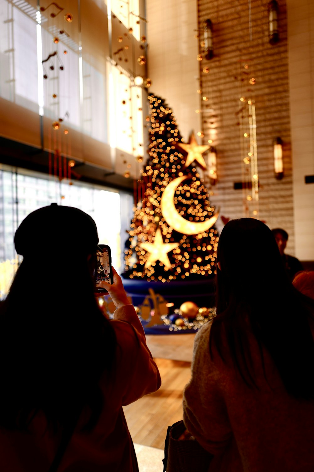 Un par de mujeres de pie frente a un árbol de Navidad