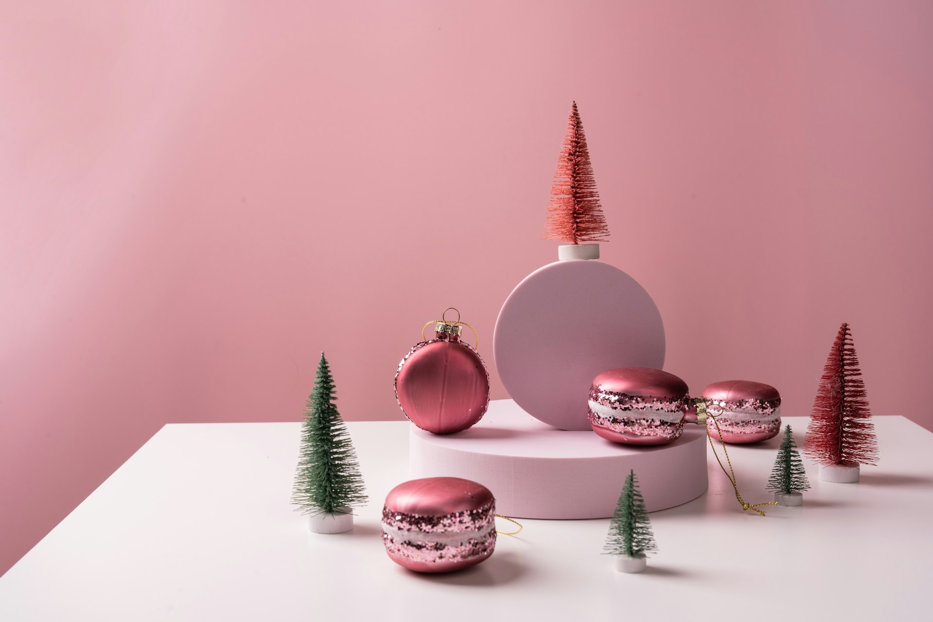 a white table topped with pink ornaments and christmas trees