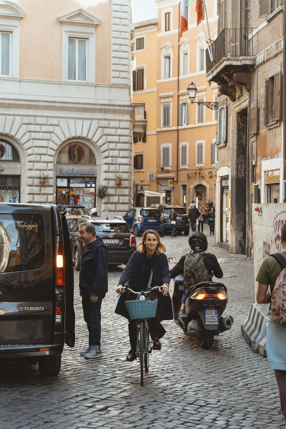 a woman riding a bike down a cobblestone street