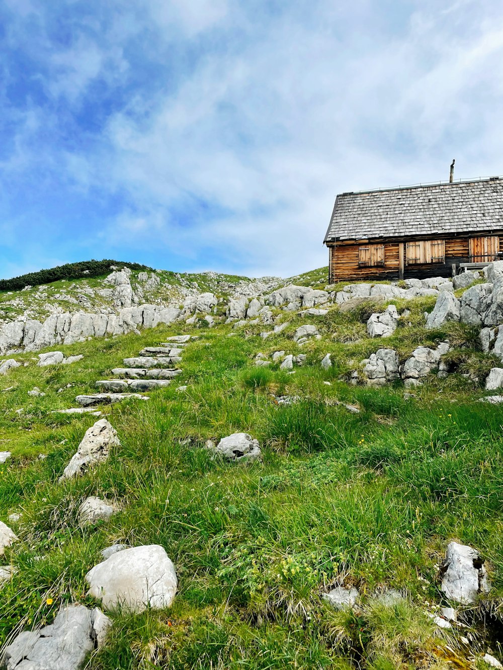 a small wooden cabin on a grassy hill