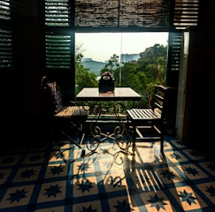 Bright seating area by the window with a small wooden table and chairs.