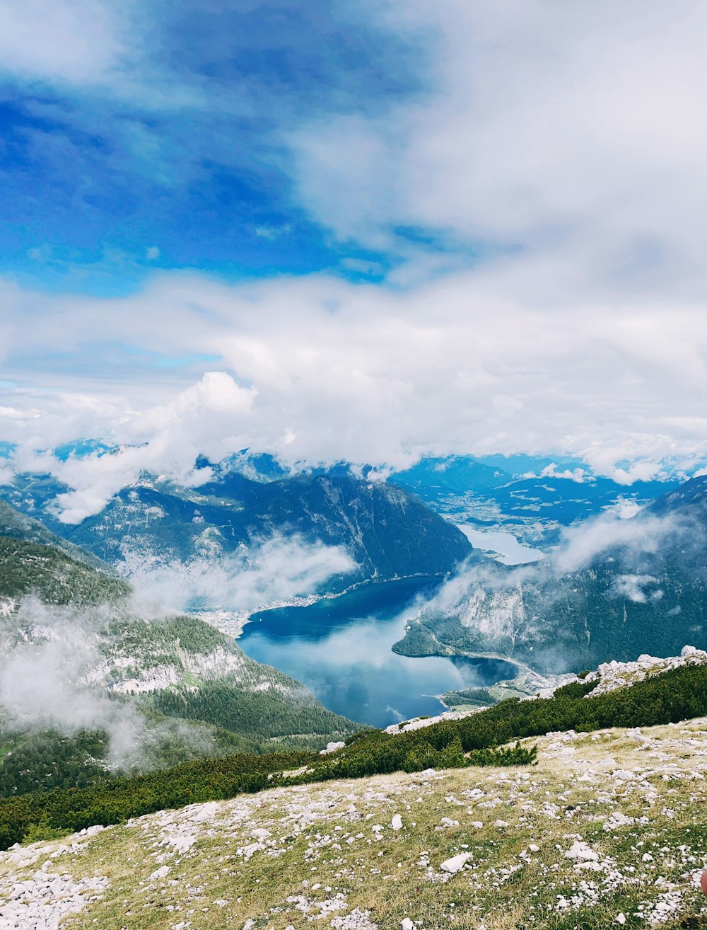 a man sitting on top of a mountain next to a lush green hillside