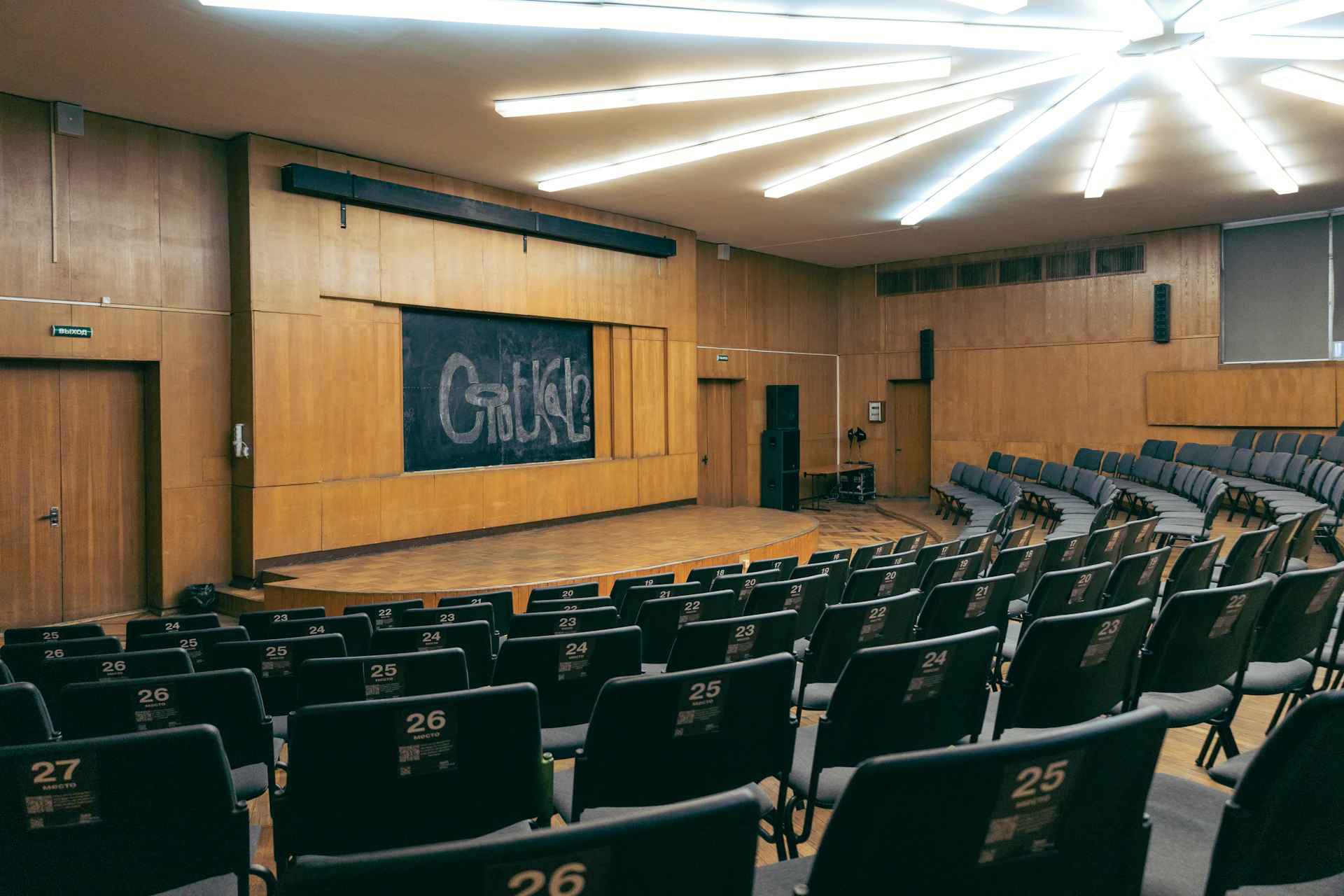 an empty auditorium with a chalkboard and chairs
