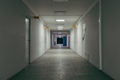 A somber, empty hospital corridor bathed in cold light, hinting at hidden stories.
