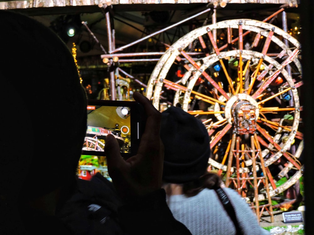a person taking a picture of a ferris wheel