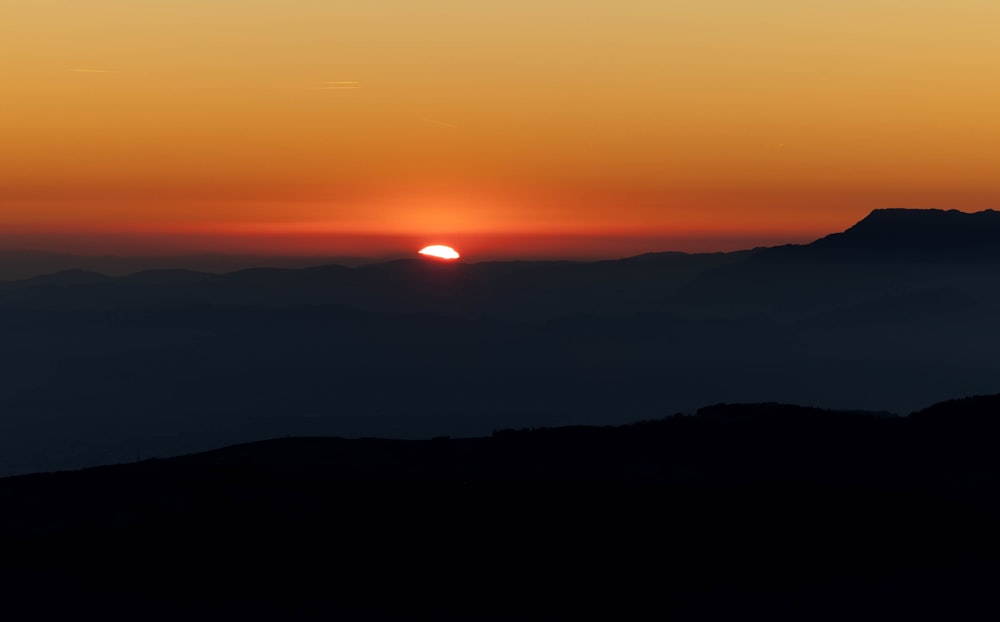 the sun is setting over a mountain range