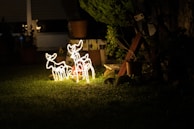 Night scene showing multiple LED reindeer figures glowing in a garden.