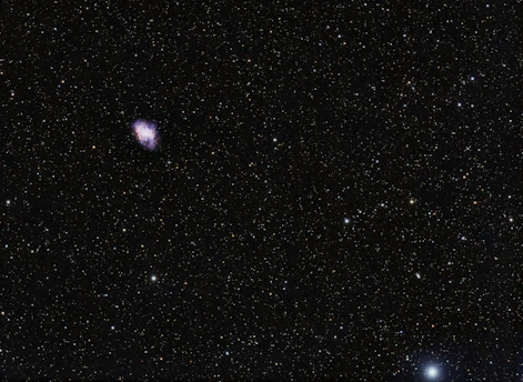 A mysterious dark blue and purple cosmic nebula with faint glowing stars.