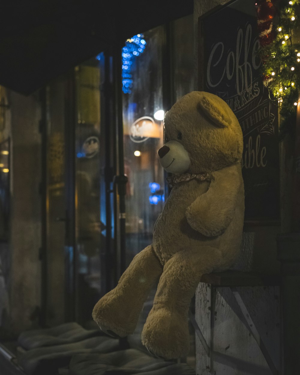 a teddy bear sitting on a ledge in front of a store