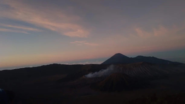 A sprawling Minecraft landscape from the 2b2t server, featuring rugged terrain and player-built structures under a sunset sky.