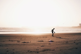 A nomad traveler kicking a football on a quiet beach at golden hour