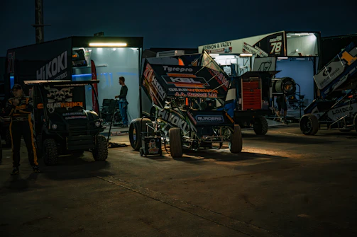 Wide shot of the team pit area illuminated by red accent lights during a night race.
