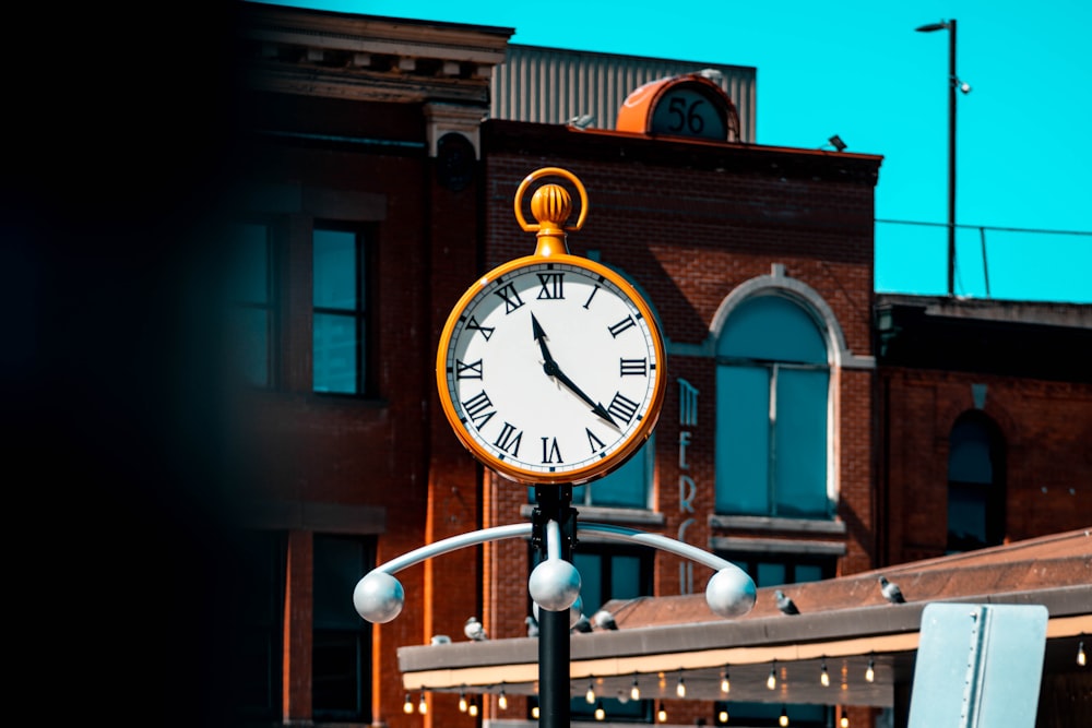 um relógio em um poste em frente a um prédio