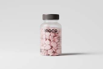 A clear plastic bottle with a gray lid is filled with light pink tablets. The bottle has the text 'MOCP' printed in black on the front along with additional information and a website link near the bottom.