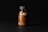 A dark-toned image showcasing a clear plastic bottle filled with orange pills under soft lighting. The bottle has a black cap and features minimalist labeling with the letters 'mocp' prominently displayed.