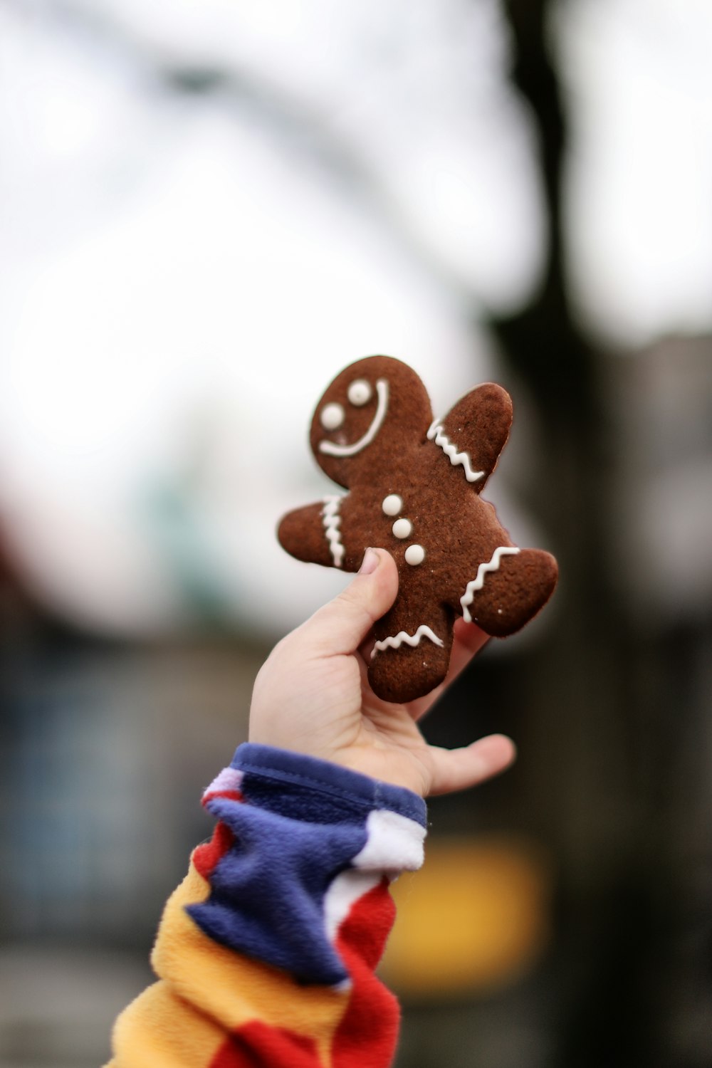 a hand holding a small brown teddy bear