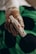 A gloved hand holds a sterile medical device, possibly for blood testing or sample collection, with a green and black background.