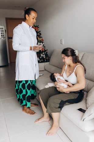 a woman holding a baby while sitting on a couch