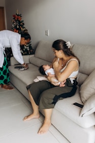 a woman sitting on a couch holding a baby